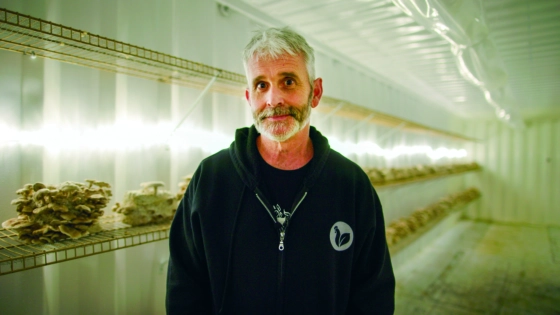 Craig Watts stands in front of mushrooms.